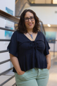 Elizabeth Fernandez, science writer in blue shirt leaning against railing